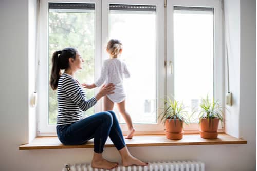 Mother and little girl looking out windows, window replacement in St. Louis concept