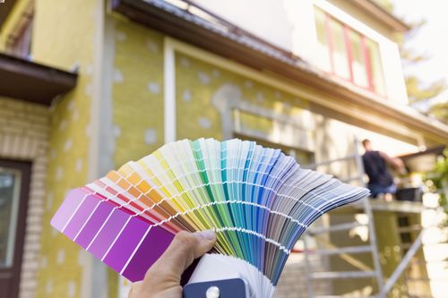 woman holding color wheel up to home concept of top trending exterior home colors in 2022